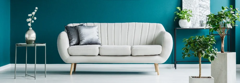 Weißes Sofa vor einer petrolfarbenen Wand